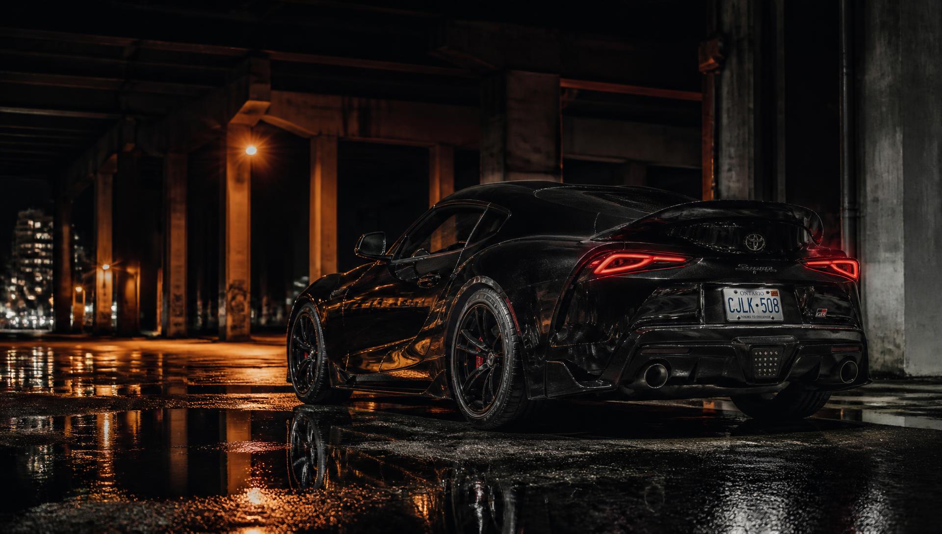 Black sports car on wet asphalt at night
